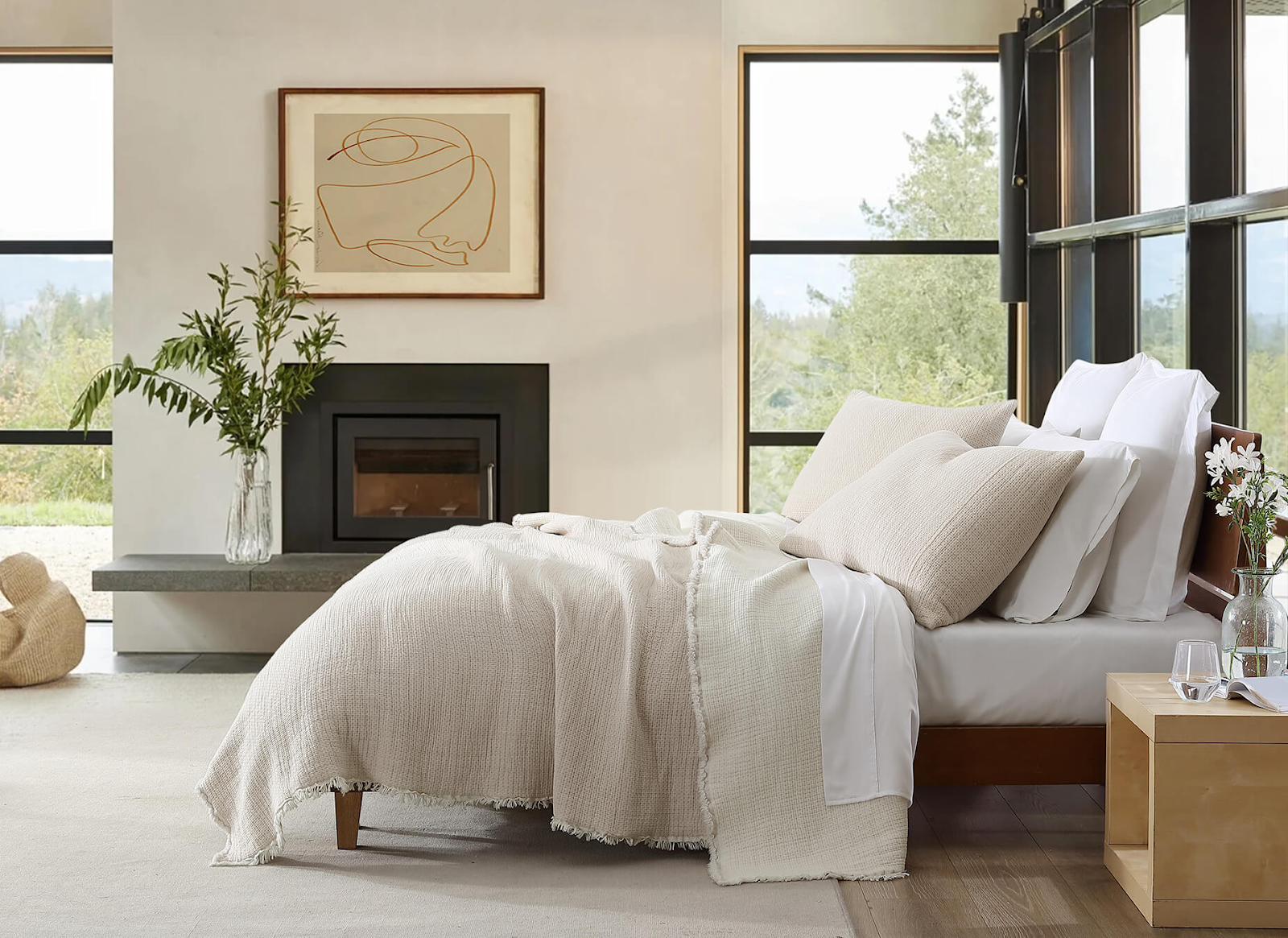A cozy bedroom setup, electric fireplace in the background with a bed in the foreground covered in fluffy bedding.