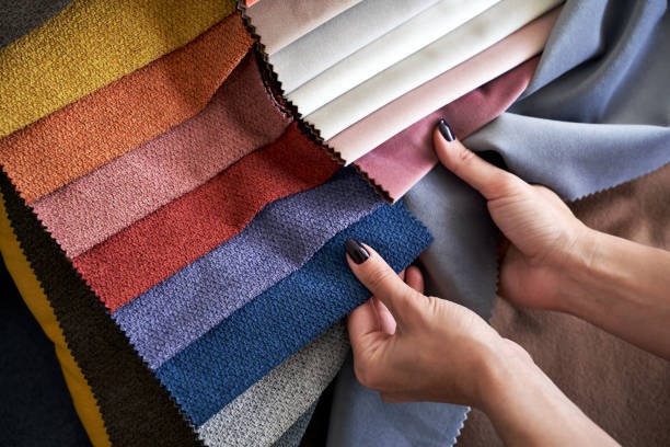 Hands holding fabric swatch samples showing different curtain colors and textures