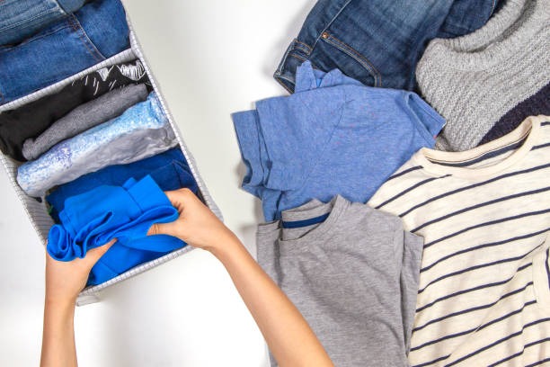 Hands of a person folding clothing into a vertical fabric tray organizer.