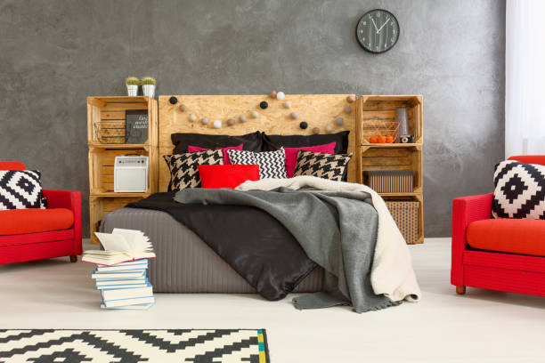 Spacious bedroom in grey with double bed, DIY regales, pattern details and two, red armchairs