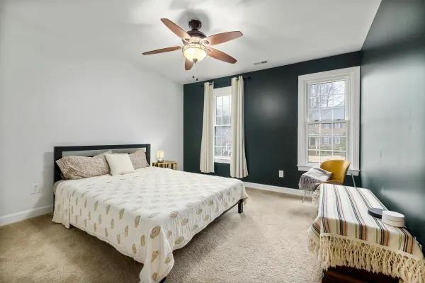 Simple bedroom with soft beige carpet and ceiling fan