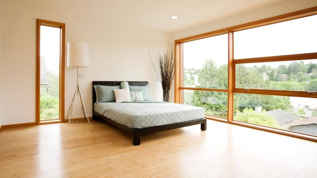 Minimalist bedroom with bamboo flooring and large windows