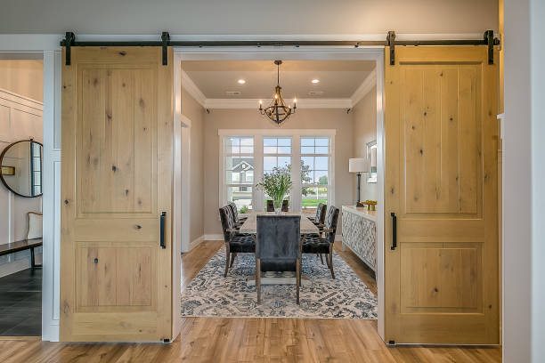Elegant dining room with sliding barn doors, wooden floors, and a view of large windows.