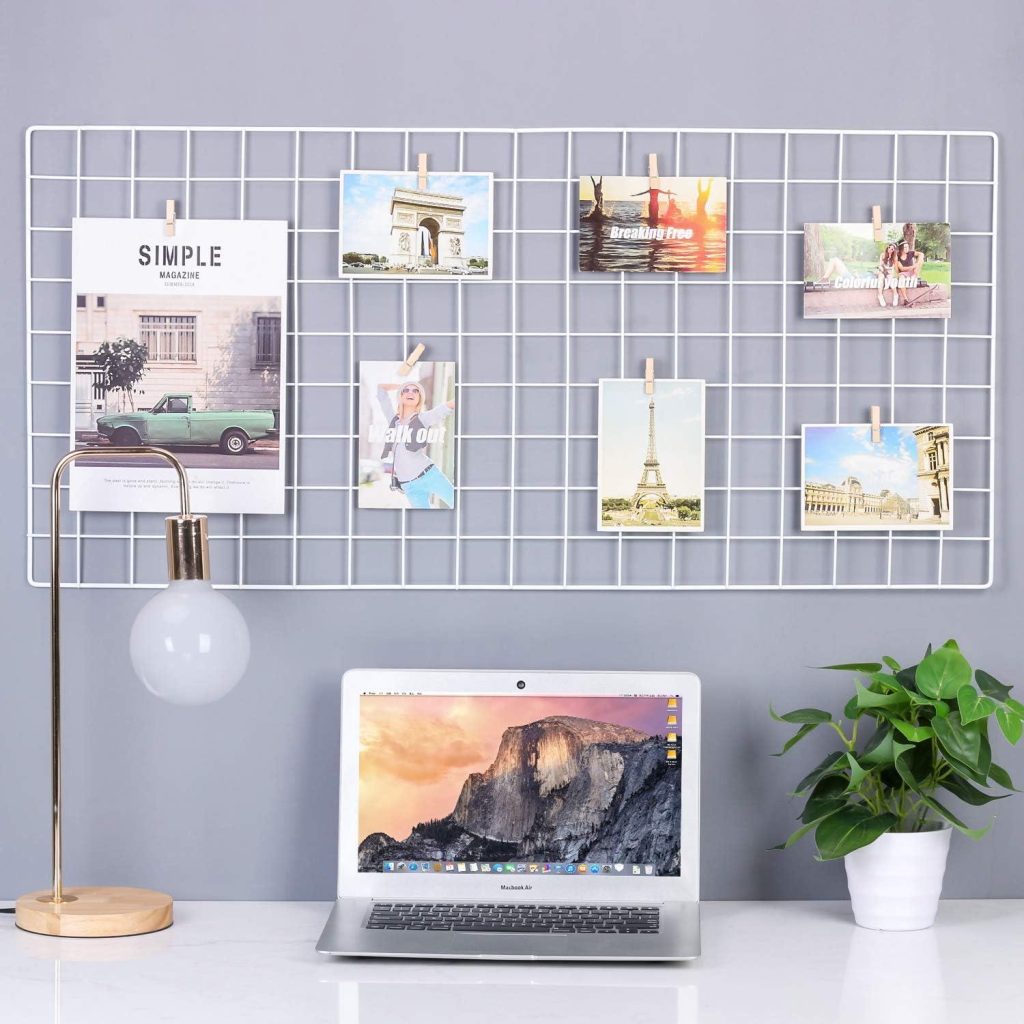 Wire grid photo display above a desk with laptop and lamp