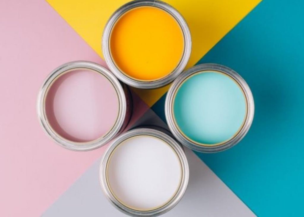 Colorful paint cans on a pastel geometric background