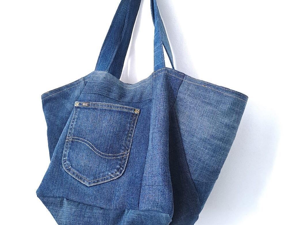 A large handmade denim tote bag crafted from upcycled jeans, featuring sturdy straps and a front pocket detail.