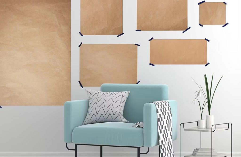 Wall layout with taped placeholders for picture frames behind a blue chair.