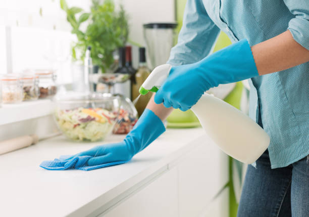 Woman cleaning and polishing the kitchen worktop with a spray detergent