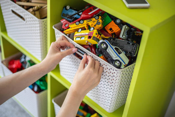Mother's hands applying children toys label to storage bin for comfortable sorting.