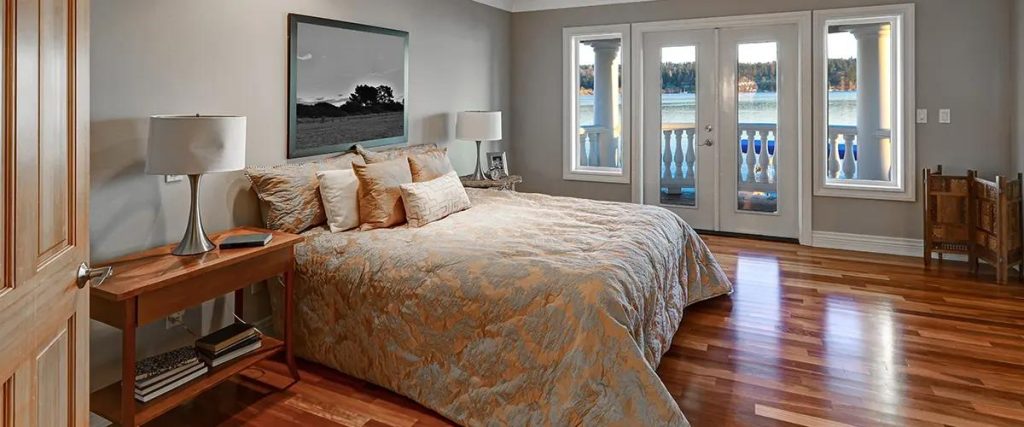 Cozy bedroom with polished wooden flooring and scenic balcony view