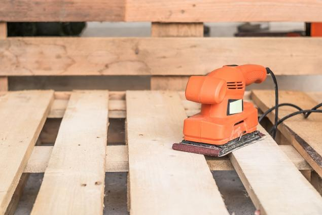 Electric sander smoothing pallet wood planks