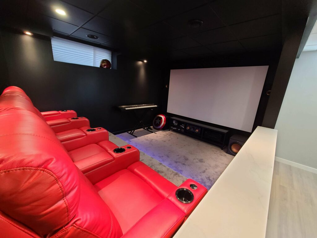 basement theater room with red recliner seats projector screen and custom cinema lighting
