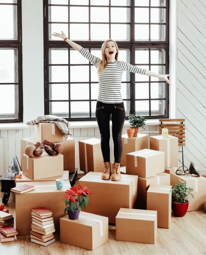 A lot of boxes laying on the floor with a woman standing on top of one cheering.