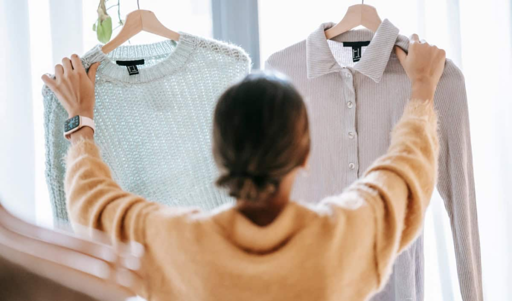 woman organizing wardrobe and choosing clothes during seasonal closet decluttering