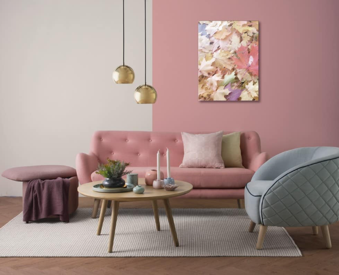 a living room with pink color palette on couch an half of a wall with and coffee table