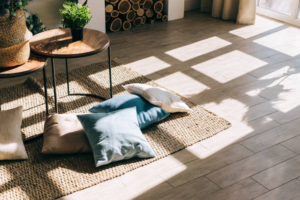 Sunlit living room with layered rugs, floor cushions, and round side table