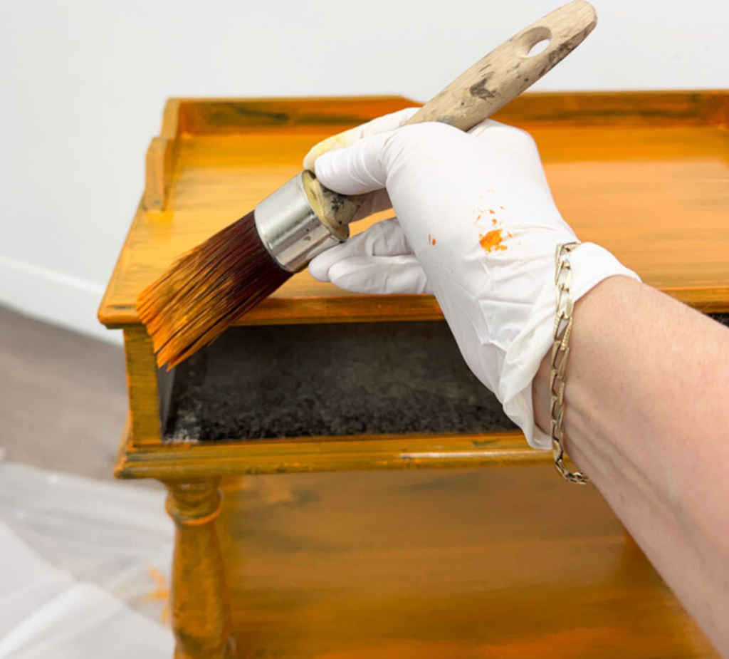 person painting a wooden side table during a diy furniture makeover project