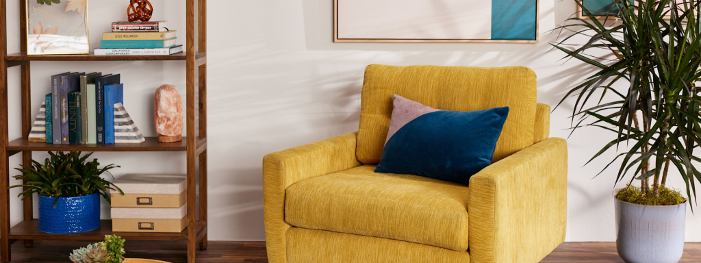 mustard yellow accent chair with blue pillow in a modern living room