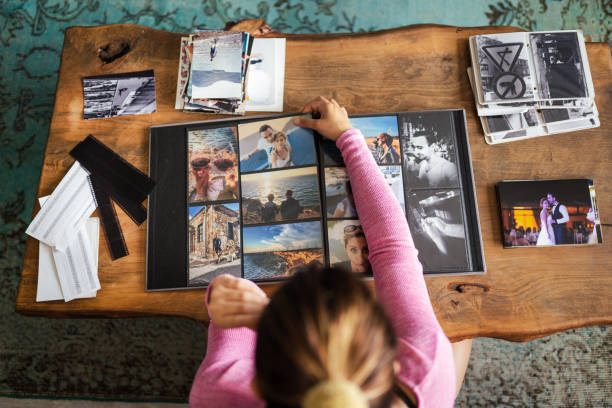 A child with her back turned organizing photos in a photo album.