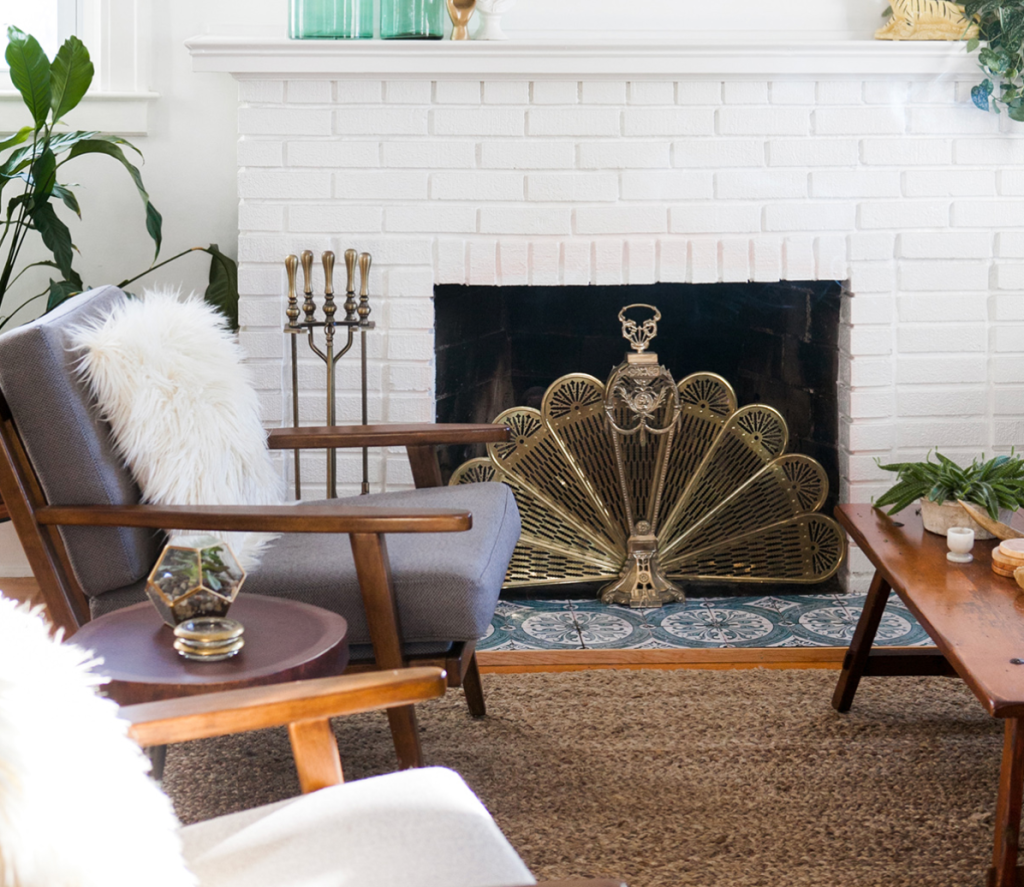 white painted brick fireplace with decorative brass screen and mid century modern furniture