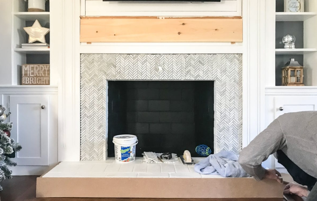 fireplace remodel with white herringbone tile surround and built in shelving