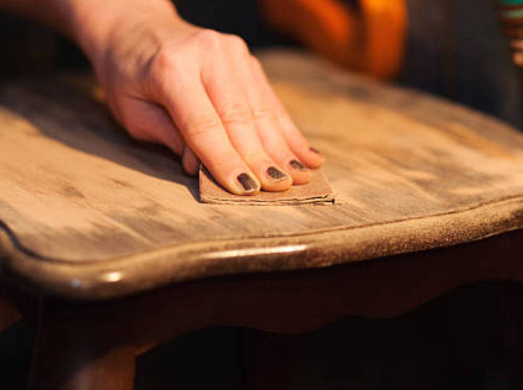 hand sanding old wooden furniture surface before refinishing