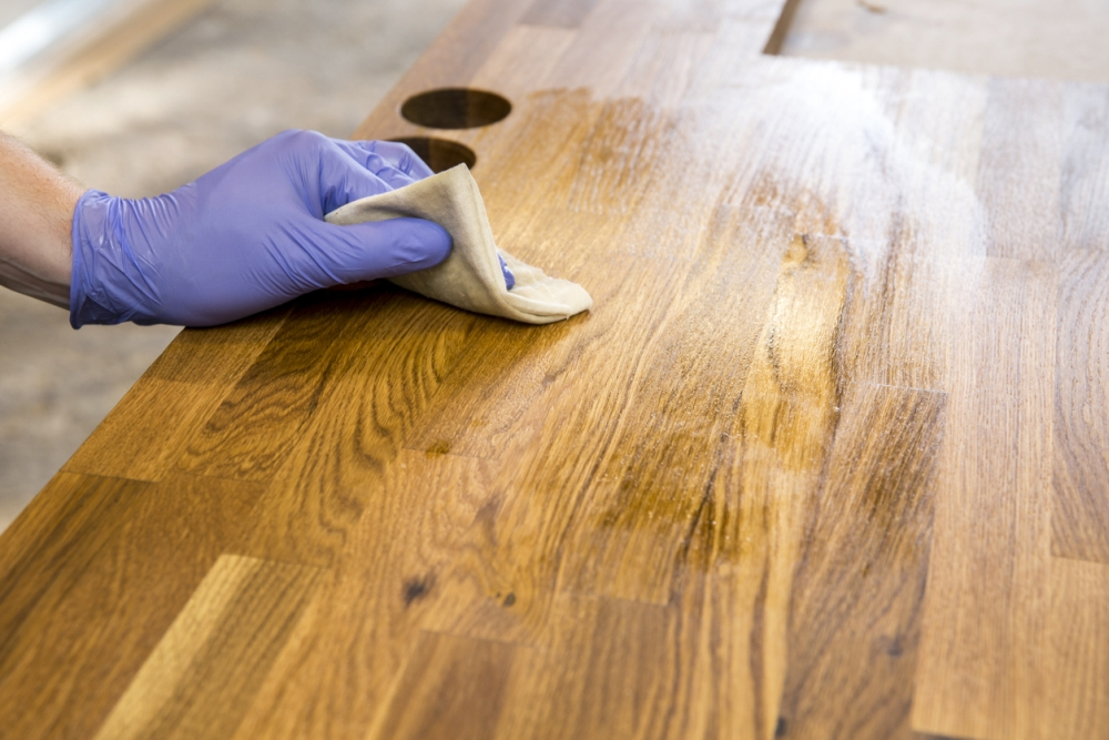 wiping wood stain onto wooden countertop for furniture restoration