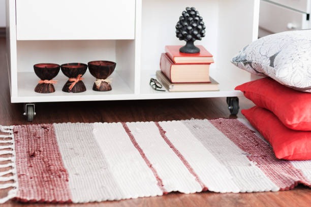 Small striped cotton rug under shelf with books and decorative cushions