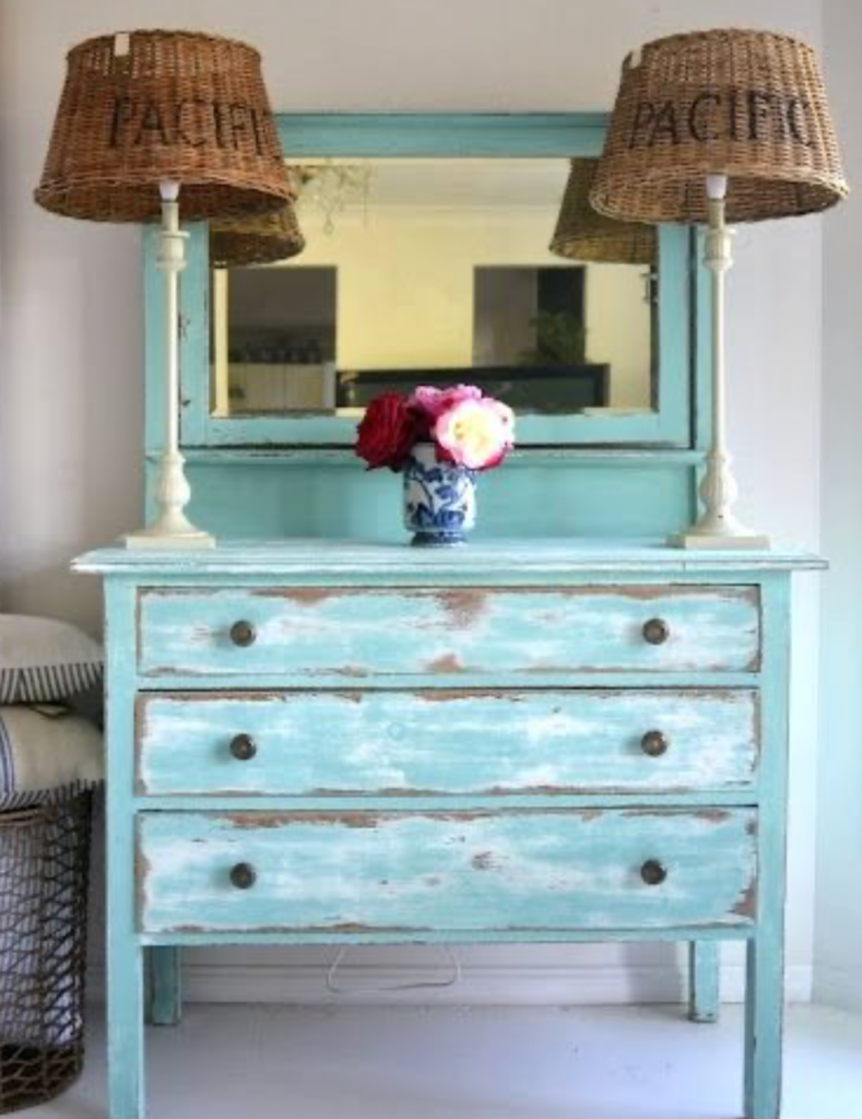 distressed blue dresser with mirror and woven lamps in a coastal style bedroom
