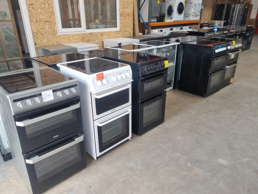 Selection of used electric cookers and kitchen ranges displayed in appliance warehouse showroom