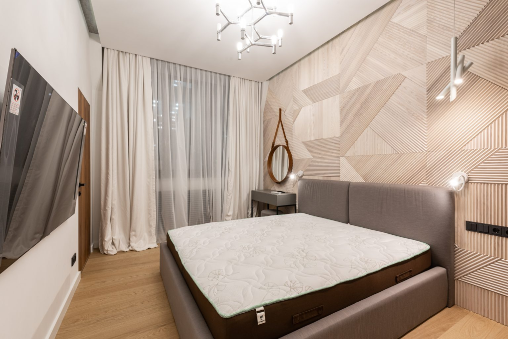 A small bedroom made larger with multiple light sources, mirrors, and curtains.