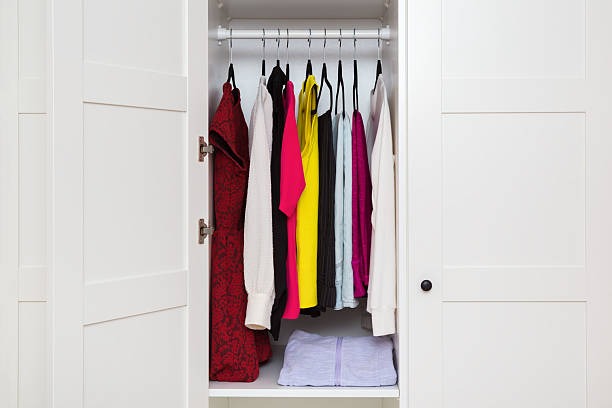 small wardrobe closet with colorful dresses and shirts hanging neatly