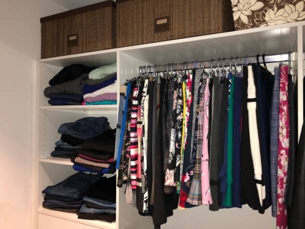 organized closet with folded clothes on shelves and garments hanging on rack