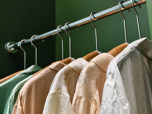 clothes neatly hanging on metal closet rod with wooden hangers for organized wardrobe storage