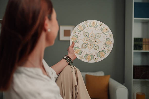Woman holding decorative patterned plate for wall decor styling in living room