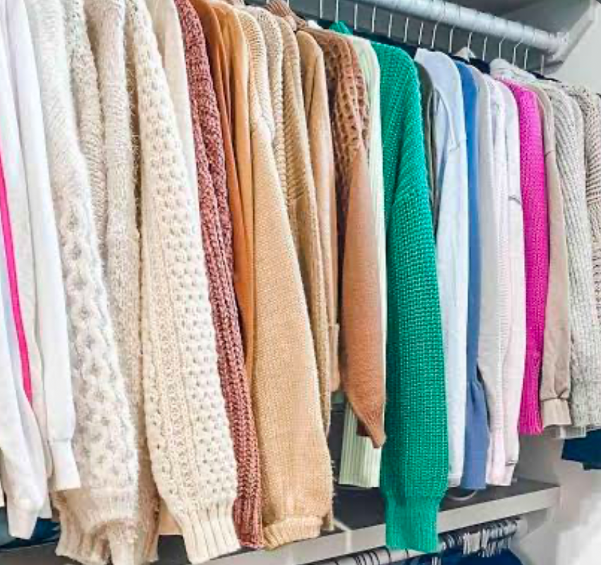 Sweaters organized in a closet.