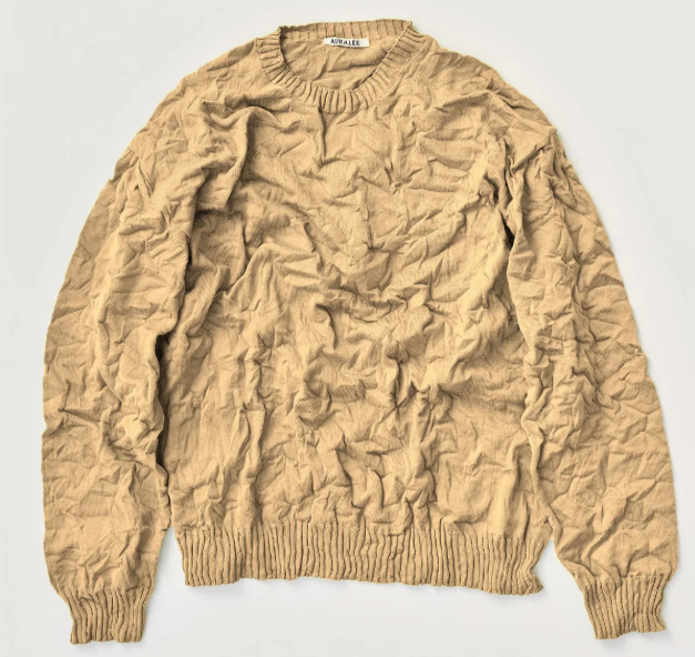Wrinkled brown sweater laying on white background.