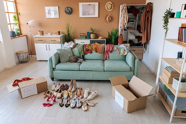 messy living room with clothes shoes and boxes during home decluttering and organization process