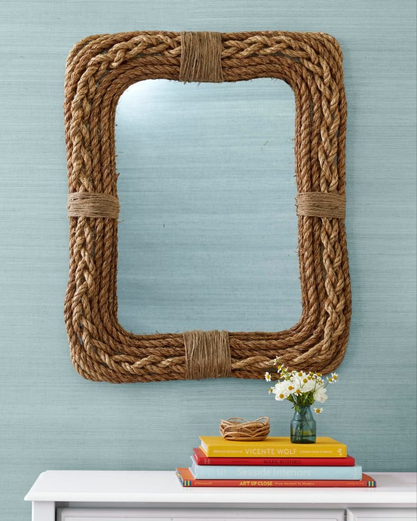 Rope-framed mirror above colorful books