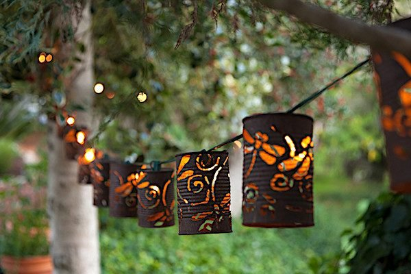 Rusted can lights hung outside with intricate designs of dragon flies.