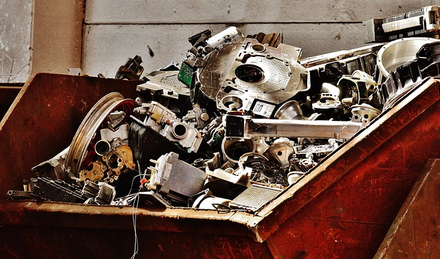 A rusty dumpster filled with shiny metal scraps of various sizes and shapes resembling what must have been parts from other machinery.
