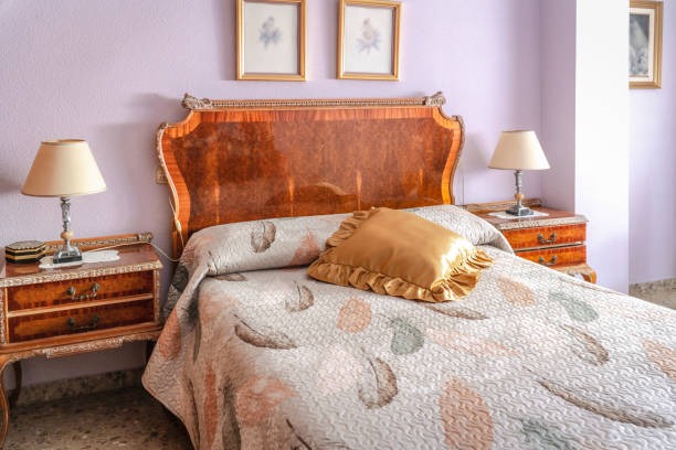 Vintage bedroom with ornate wooden headboard, matching nightstands, and pastel bedding with decorative pillow.