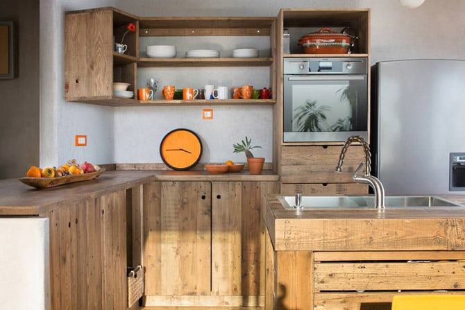 Rustic kitchen with pallet wood cabinets, open shelving, and a stainless steel sink