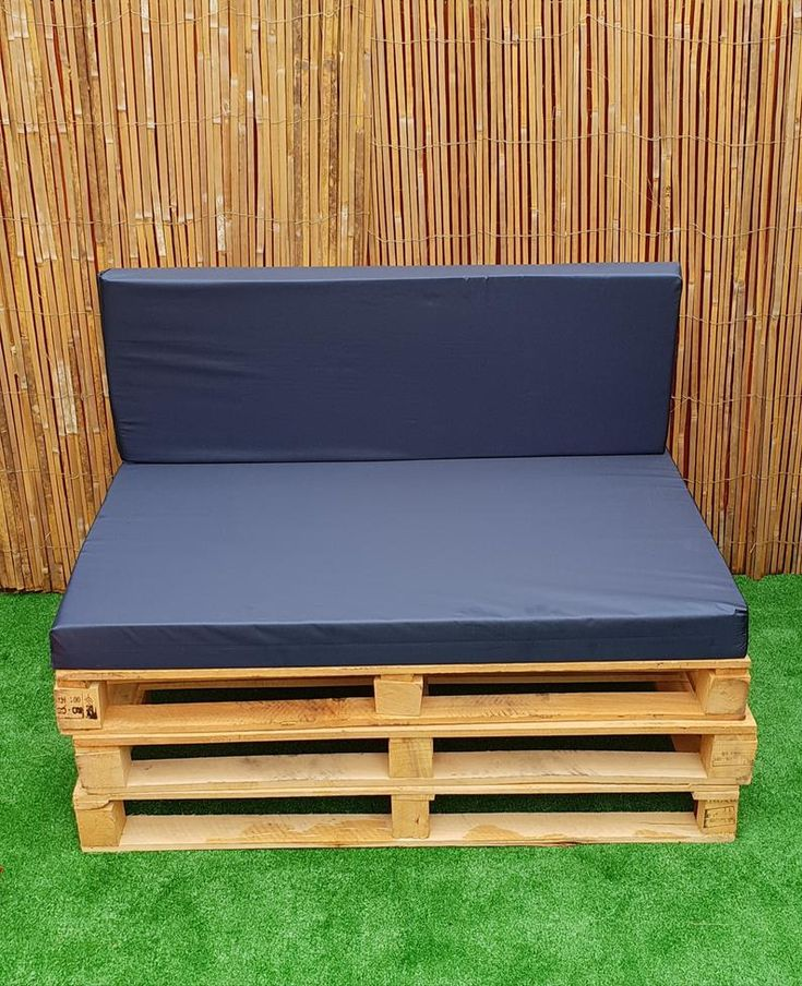 Outdoor bench made from wooden pallets with navy blue cushions.
