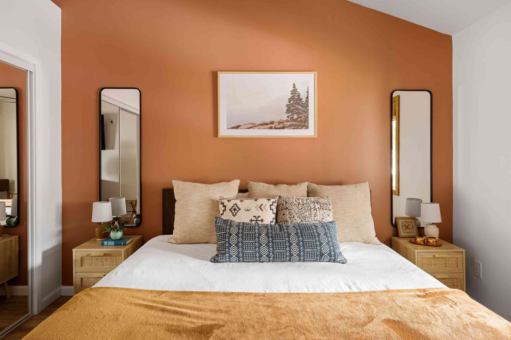 A bedroom with a orange accent wall. All other walls are white.
