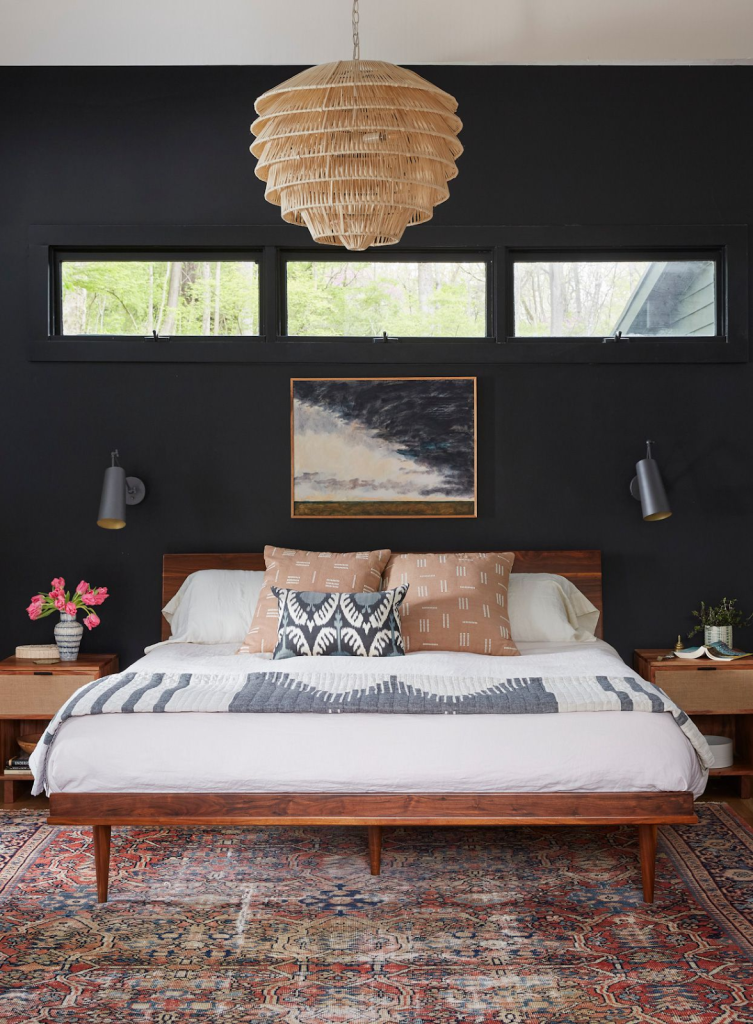 Black accent wall in a bedroom with dark wood furniture.