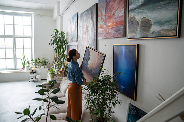Paintings being placed onto a large wall by an artist.