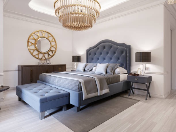 Elegant classic bedroom with tufted grey headboard, chandelier lighting, and coordinated furniture décor