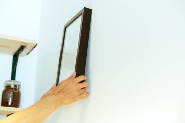 Hands placing a clean frame on a wall.