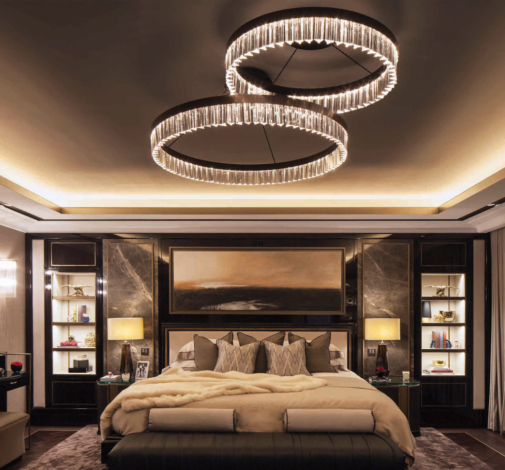 Layers of lighting in a luxury bedroom from a circular pair of chandeliers to led concave ceiling LEDs to wall scones and in cabinet lighting.